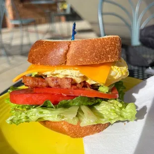 Bacon egg and cheese breakfast sandwich with avocado, lettuce and tomato.