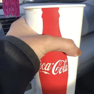 a hand holding a coca cola cup