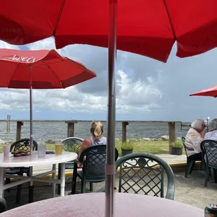 people sitting at tables with red umbrellas