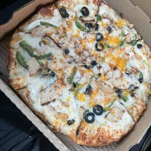 Garlic chicken pizza with extra cheese no red onions added bell peppers and olives.