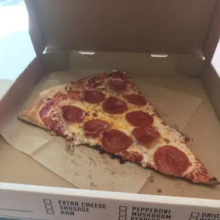 A slice of Pepperoni Pizza, almost takes up the whole box.