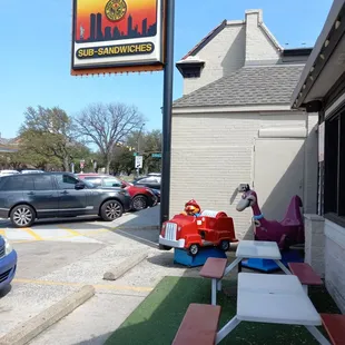 The New York Sub entrance with a couple kiddie rides and picnic tables and 4 or 5 dedicated parking spaces.