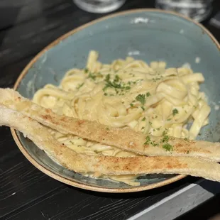 a plate of pasta and breadsticks