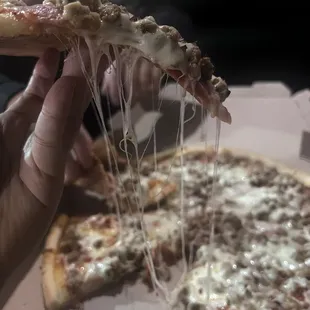 a hand holding a slice of pizza