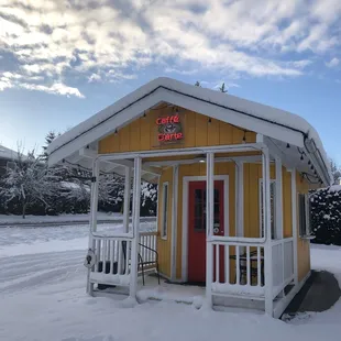 a small yellow building with a red door