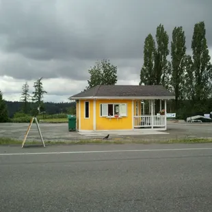 a small yellow building on the corner of a road