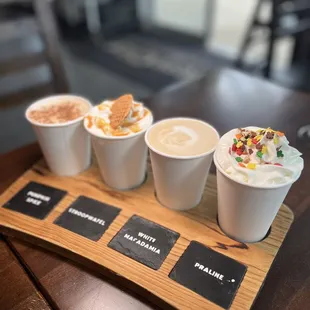 four cups of coffee on a wooden tray