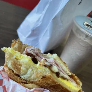 Bacon, Ham, cheese, egg croissant.   Iced Mocha in the background.