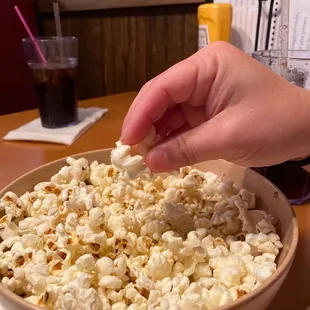 a person scooping popcorn into a bowl