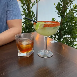 a man sitting at a table with two cocktails