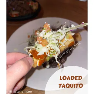 a plate of food with a hand holding a piece of food