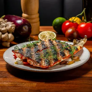 a plate of grilled fish on a wooden table