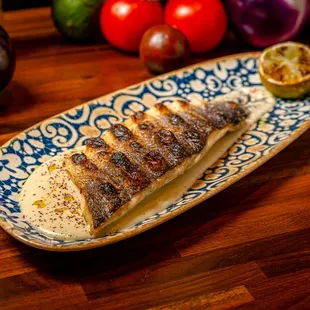 a plate of grilled fish on a wooden table