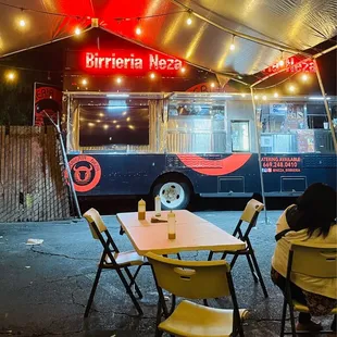 a woman sitting at a table in front of a bus