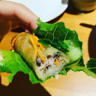 a person holding a sandwich with lettuce and cheese