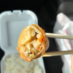 a person holding a piece of food with chopsticks