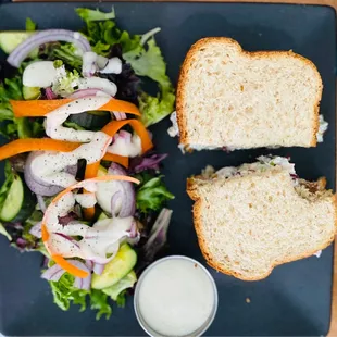 The first bite. Nibbles Eatery chicken salad sandwich on fresh bread, side salad with ranch dressing and a side of ranch dressing.
