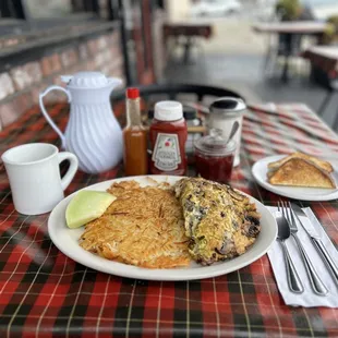 House Omelette, hash browns, sourdough toast, house coffee in a white carafe, and homemade strawberry jam.