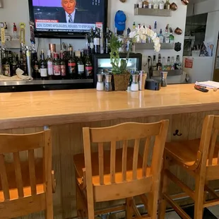 a bar with wooden chairs and a flat screen tv