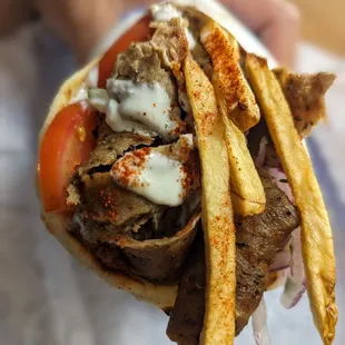 a hand holding a sandwich and french fries