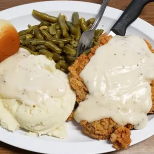 a plate of fried chicken with gravy and mashed potatoes