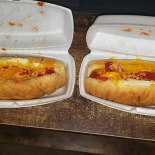 Two cheese hot dogs  with ketchup on it