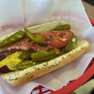a hot dog with pickles and tomatoes