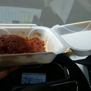 a hand holding a takeout container