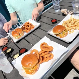 a table full of burgers and onion rings