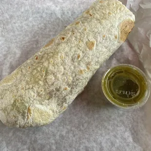 Vegetarian deluxe burrito with green salsa on the side.