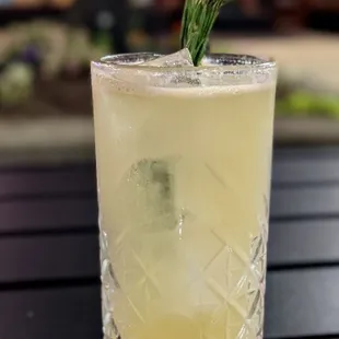 a glass of lemonade with a sprig of rosemary