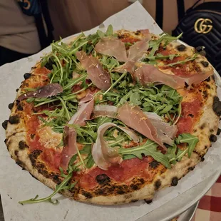 a pizza with arugula and prosciutto