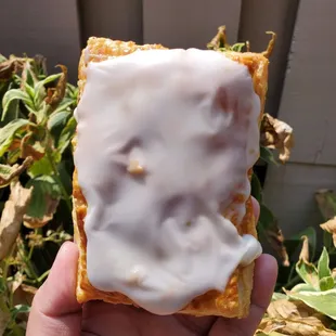 a hand holding a pastry with icing