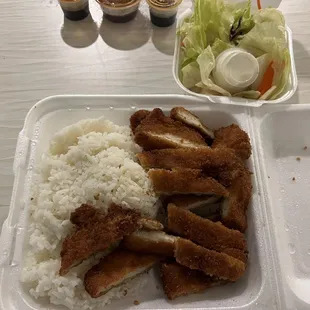 a plate of rice, chicken, and salad