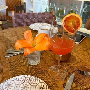 a table setting with a glass of orange juice and a plate of silverware