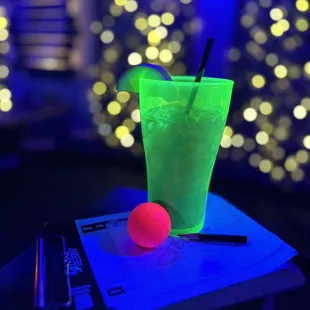 a green drink and a pink ball on a table