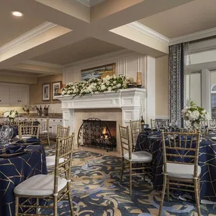 a banquet room set up with blue linens and gold chairs