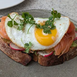 Smoked salmon &amp; avocado toast - smashed avocado, radish, cherry tomatoes, pickled onions, sesame-quinoa topping, fried egg