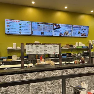 a restaurant counter with menus on the wall