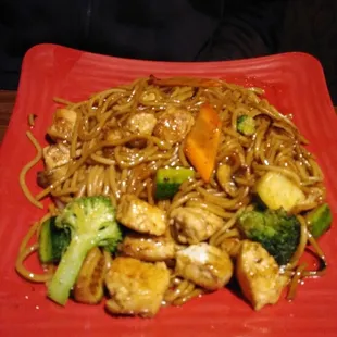 a plate of noodles with chicken, broccoli and carrots
