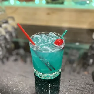 a blue drink with a red cherry