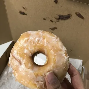 a hand holding a glazed donut