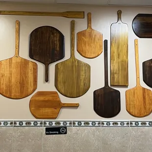 a variety of wooden pizza paddles on a wall