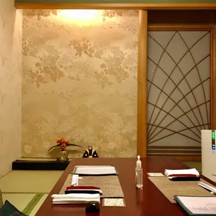 a room with a table, chairs, and a refrigerator