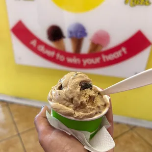 a hand holding a cup of ice cream