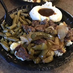 Steak tips over rice with peppers and onions