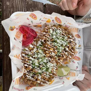 a person holding a plate of nachos