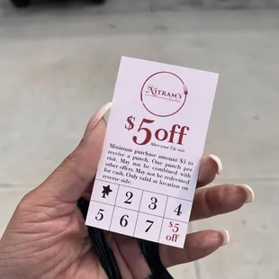 a hand holding a $ 5 off coup card