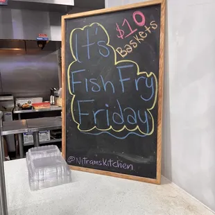 a chalk board with a price list for fish fry friday