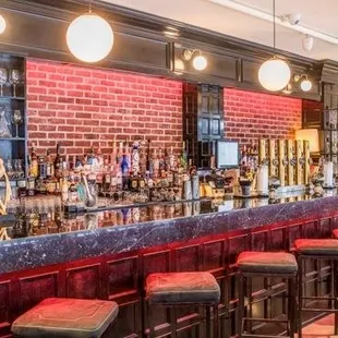 a bar with stools and a brick wall